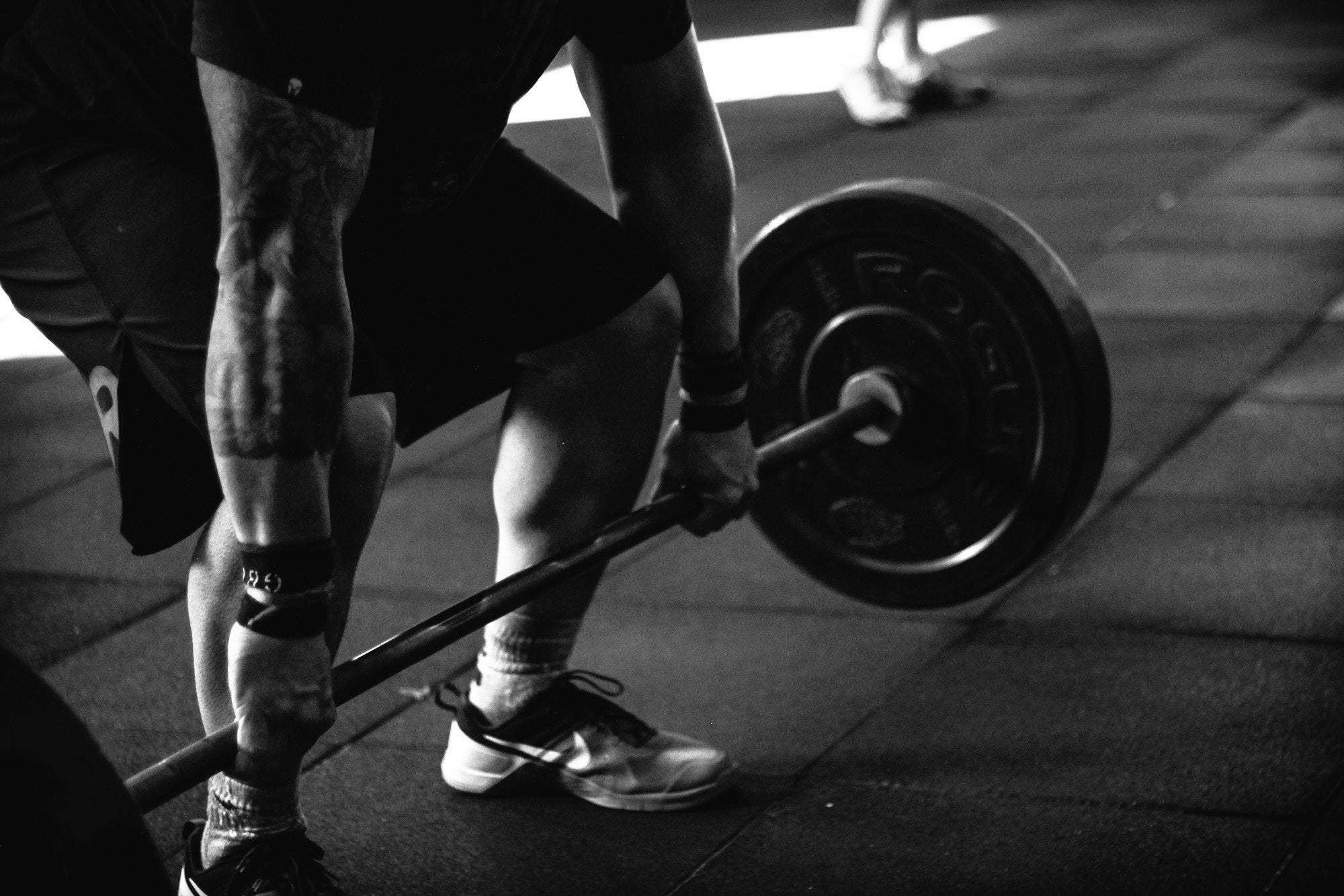 man lifting bar bell to build muscle. Black and white photo